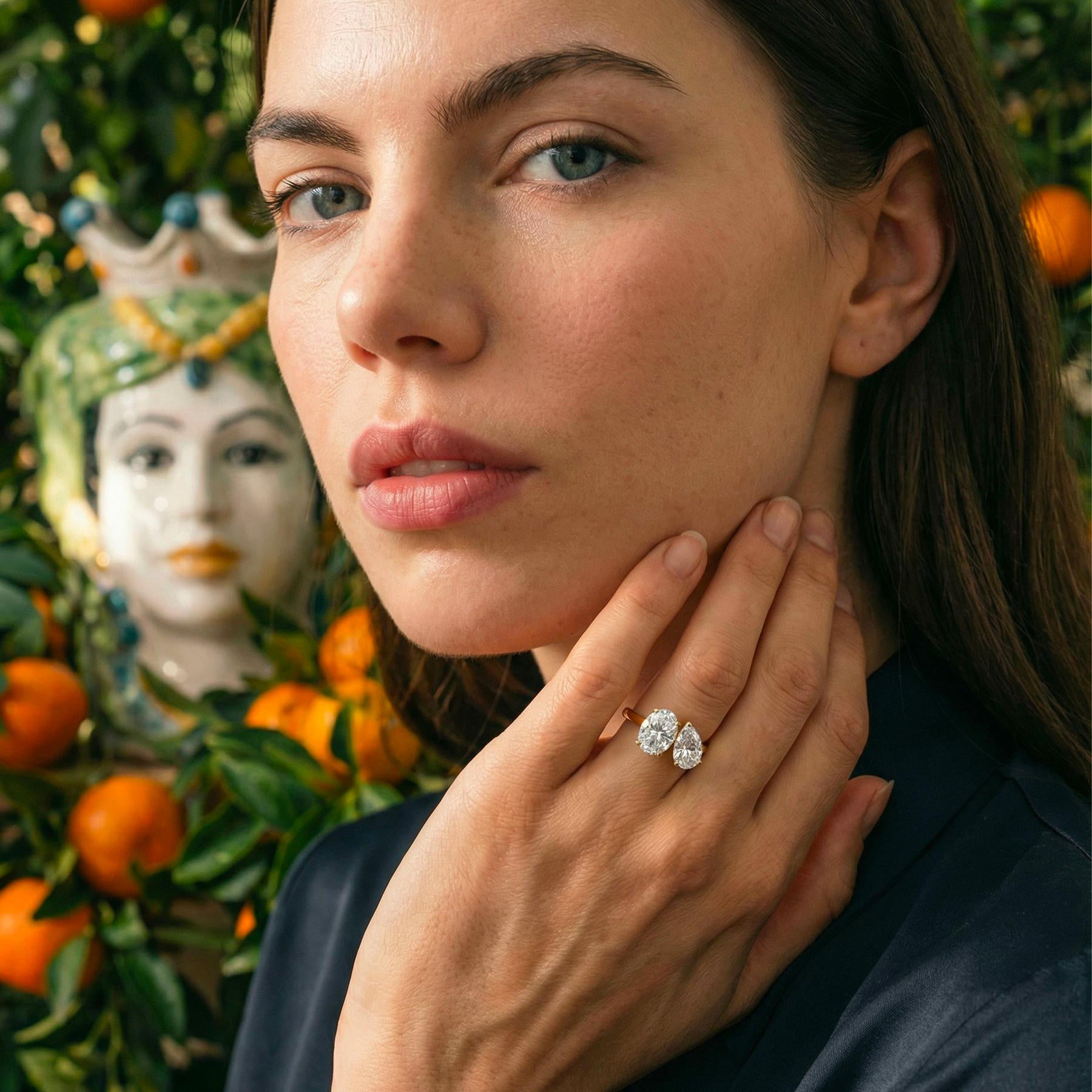 Bague de fiançailles Toi et Moi Maison Mandarine en or 18 carats avec diamants taille ovale et poire portée par une femme devant un mandarinier